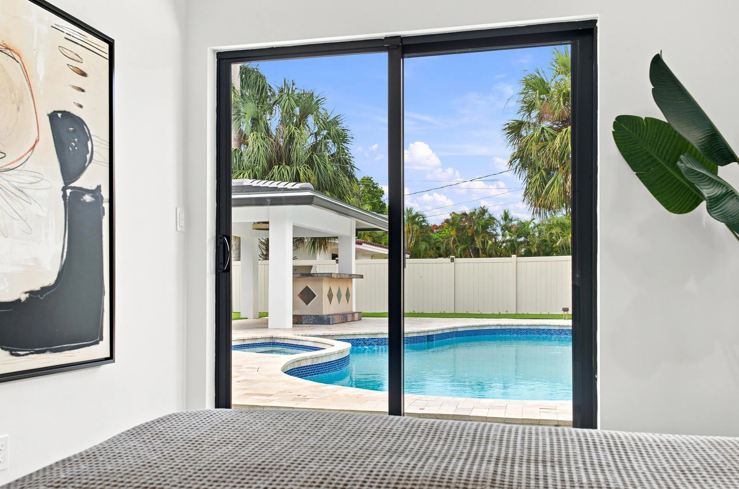 Sliding glass doors opening to a backyard featuring a swimming pool with integrated spa, a gazebo, and a built-in outdoor bar