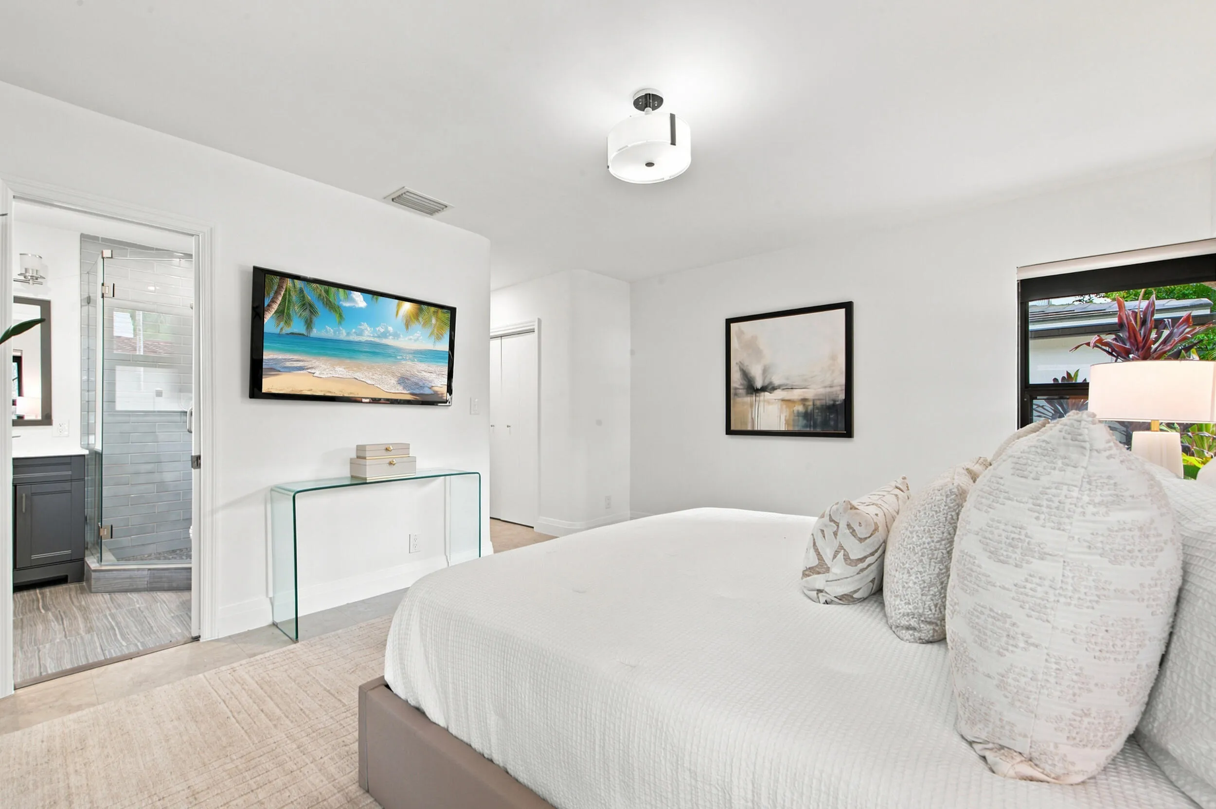 Bedroom featuring an en-suite bathroom with a glass-enclosed shower, a vanity with a dark wood-finish cabinet, and a large window providing natural light