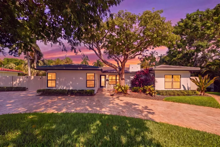 Contemporary residence featuring a paved driveway, mature trees, and landscaped grounds