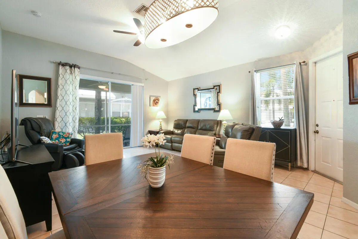 Open concept living area featuring vaulted ceilings, a wood-finish dining table, ceramic tile flooring, and sliding glass doors to the exterior