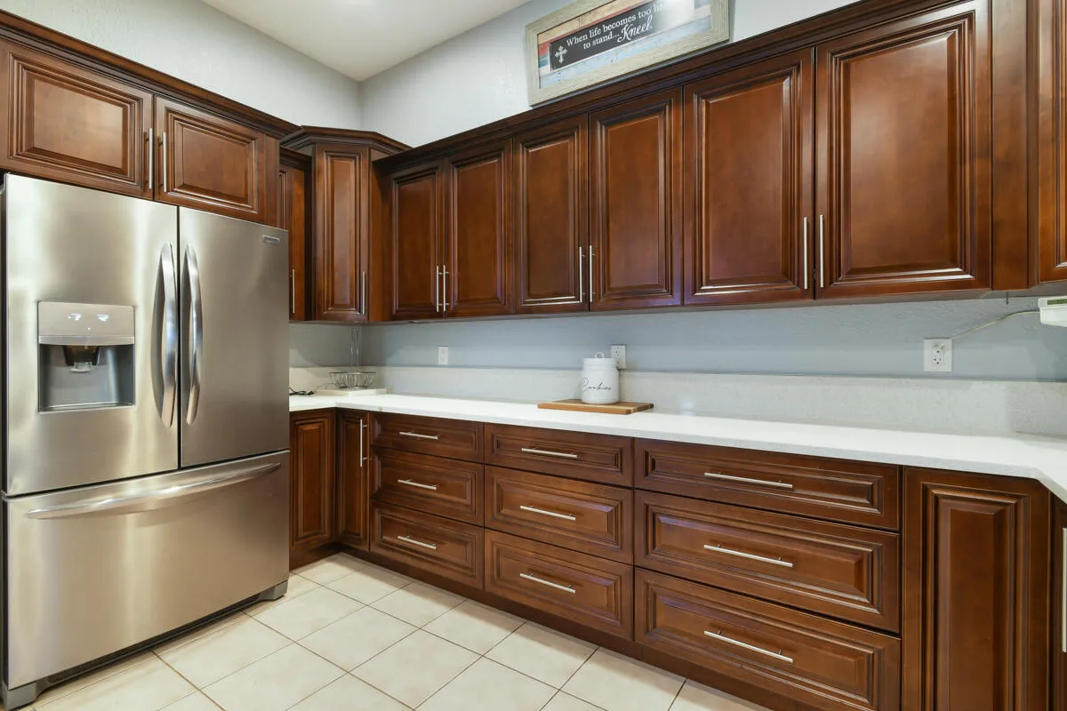Kitchen featuring rich wood cabinetry, stainless steel French door refrigerator, light-toned countertops, and tile flooring