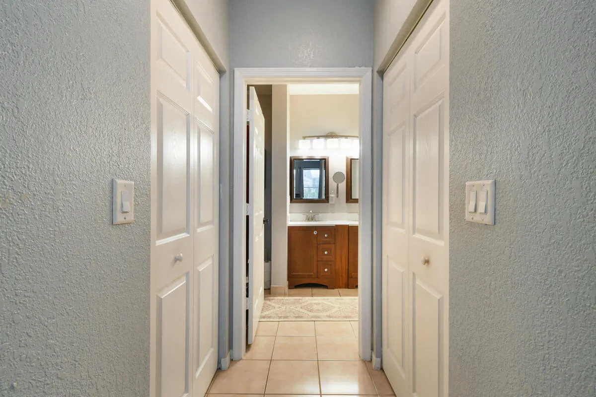 Hallway with bi-fold closet doors, textured walls, and tile flooring