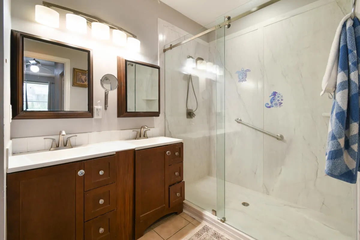 Double vanity with undermount sinks, wood-finish cabinetry, and framed mirrors