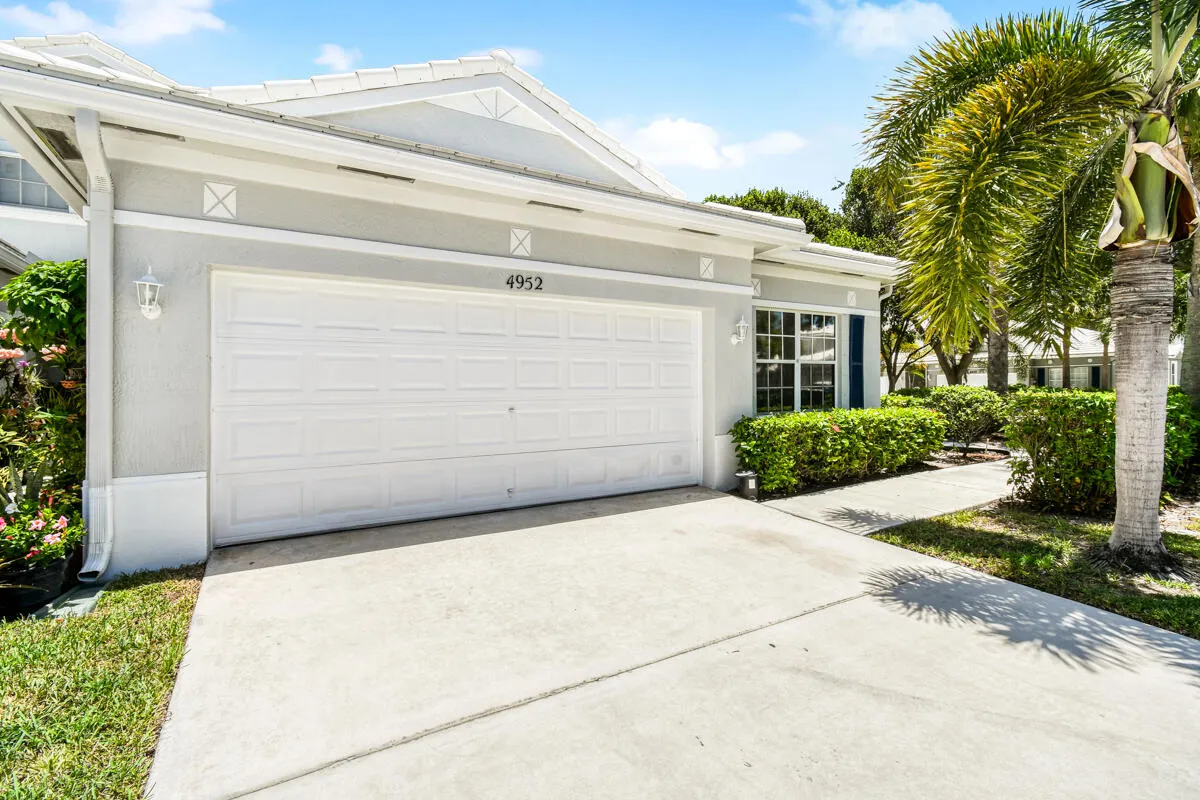 Front exterior featuring a white garage door, concrete driveway, and stucco siding