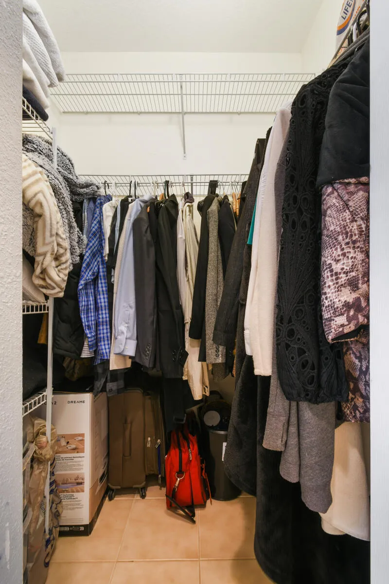 Walk-in closet featuring wire shelving, multiple hanging rods, and tile flooring