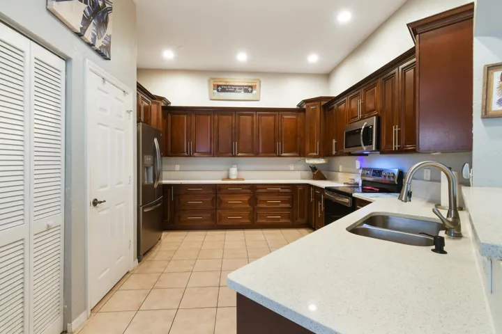 Kitchen featuring dark wood cabinetry, white countertops, stainless steel appliances, and recessed lighting