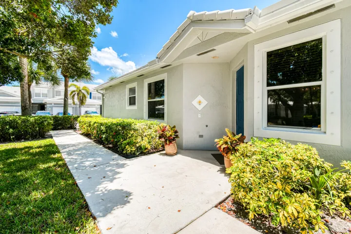 Concrete walkway leading to a blue entry door with a decorative wall accent