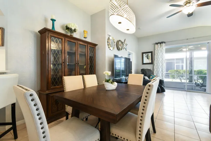 Dining area featuring tile flooring, a decorative chandelier, and an adjacent enclosed patio with sliding glass doors