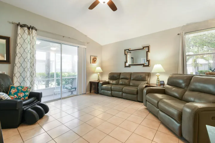 Spacious living area featuring vaulted ceilings, tile flooring, and large sliding glass doors opening to a screened enclosure