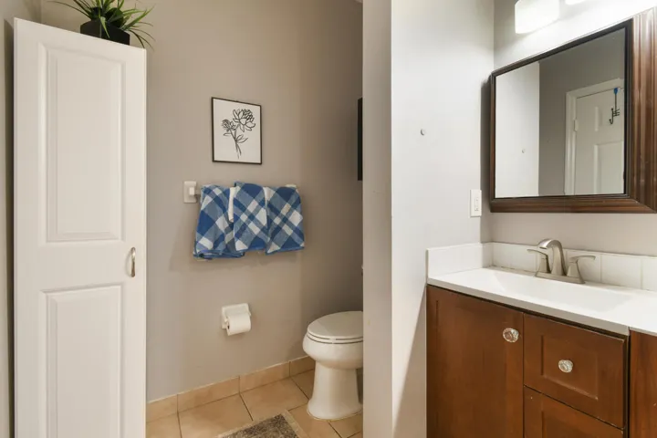Bathroom featuring a vanity with a white countertop and wood-finish cabinetry, a framed mirror, and a white toilet