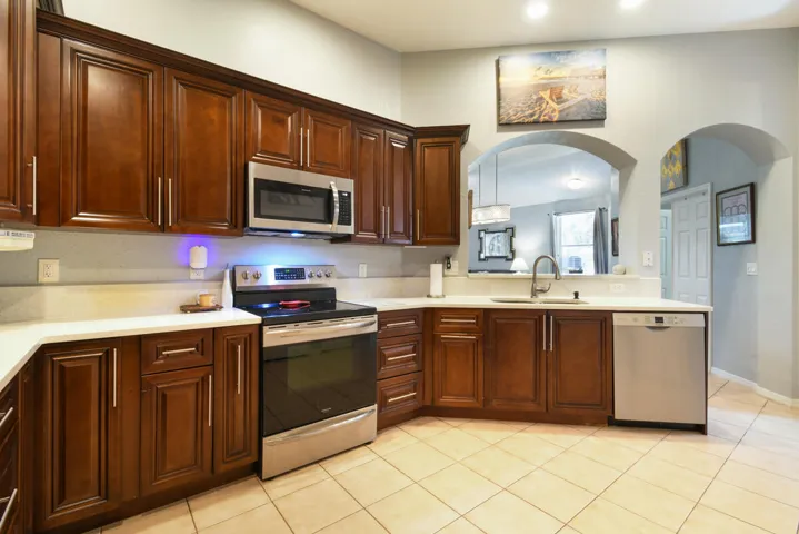 Kitchen featuring wood-finish cabinetry, light-toned countertops, and stainless steel appliances including a microwave, range, and dishwasher