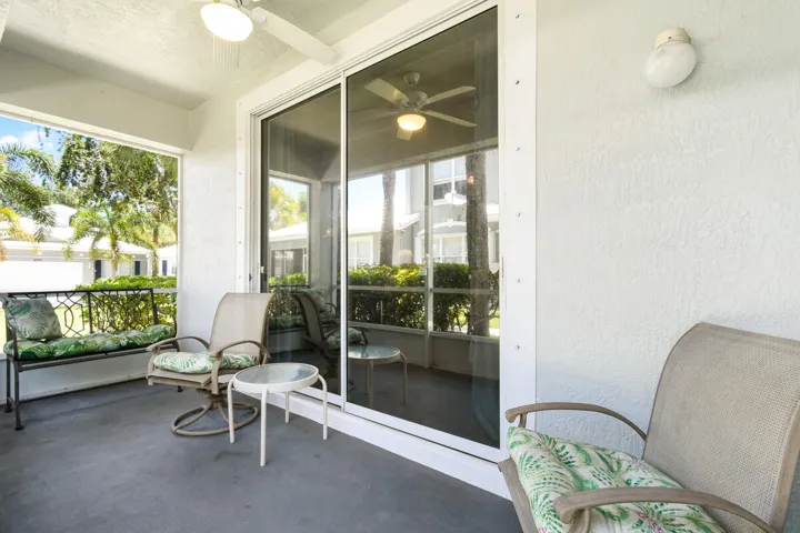Screened lanai featuring a ceiling fan, textured white walls, and a sliding glass door