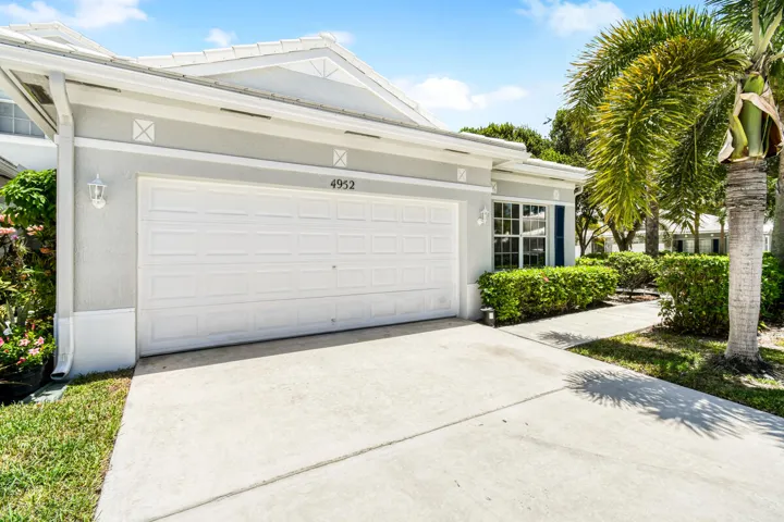 Front exterior featuring a white garage door, concrete driveway, and stucco siding