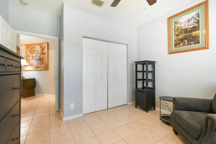 Room featuring light-toned tile flooring, light gray walls, and a white bi-fold closet