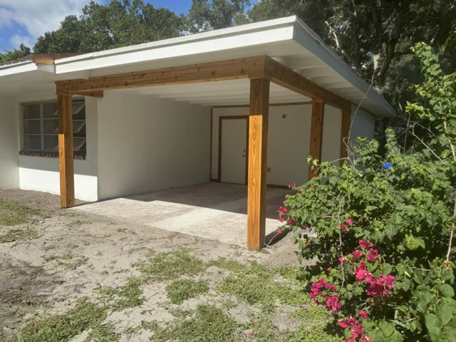Covered entry with wooden support beams and a concrete pad