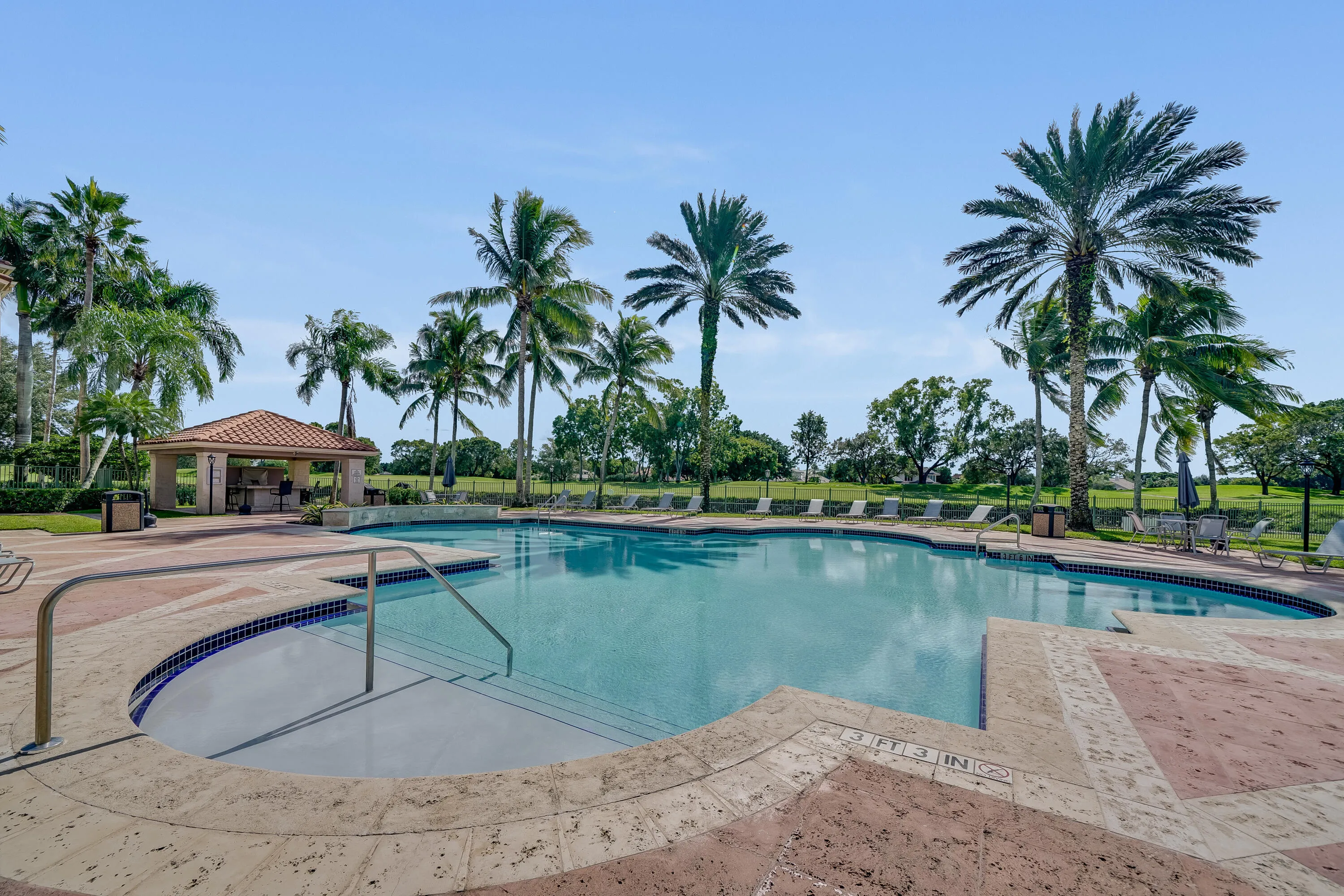Expansive outdoor swimming pool with integrated spa, surrounded by a paver deck