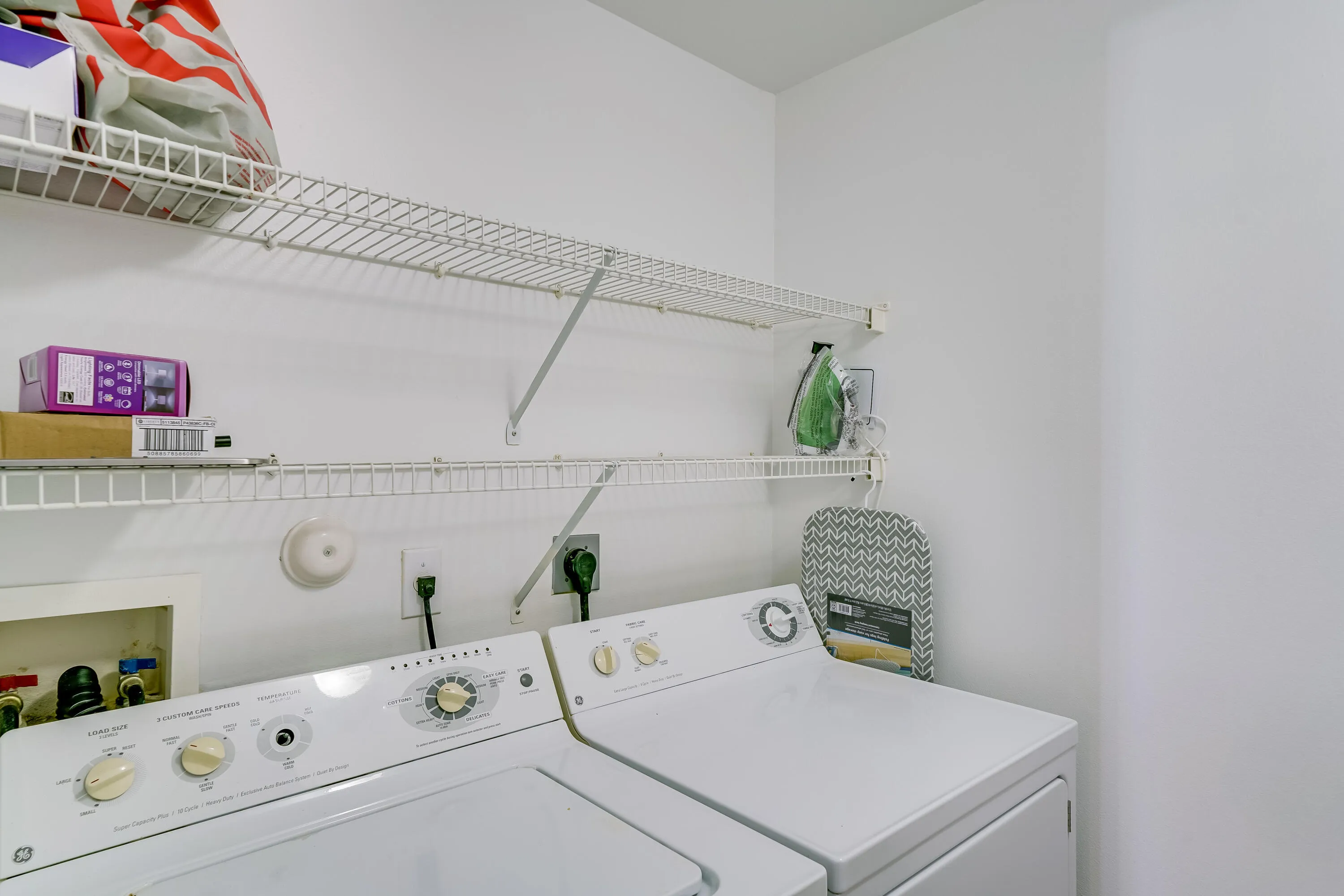 Dedicated laundry area featuring a washer and dryer, integrated wire shelving, and overhead storage