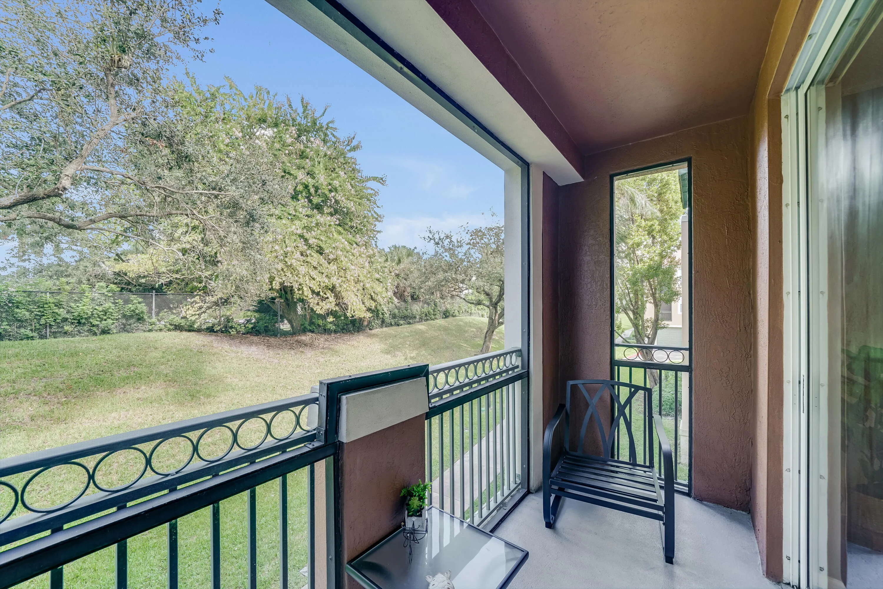 Balcony featuring a decorative black metal railing, concrete flooring, and an exterior wall with a textured finish