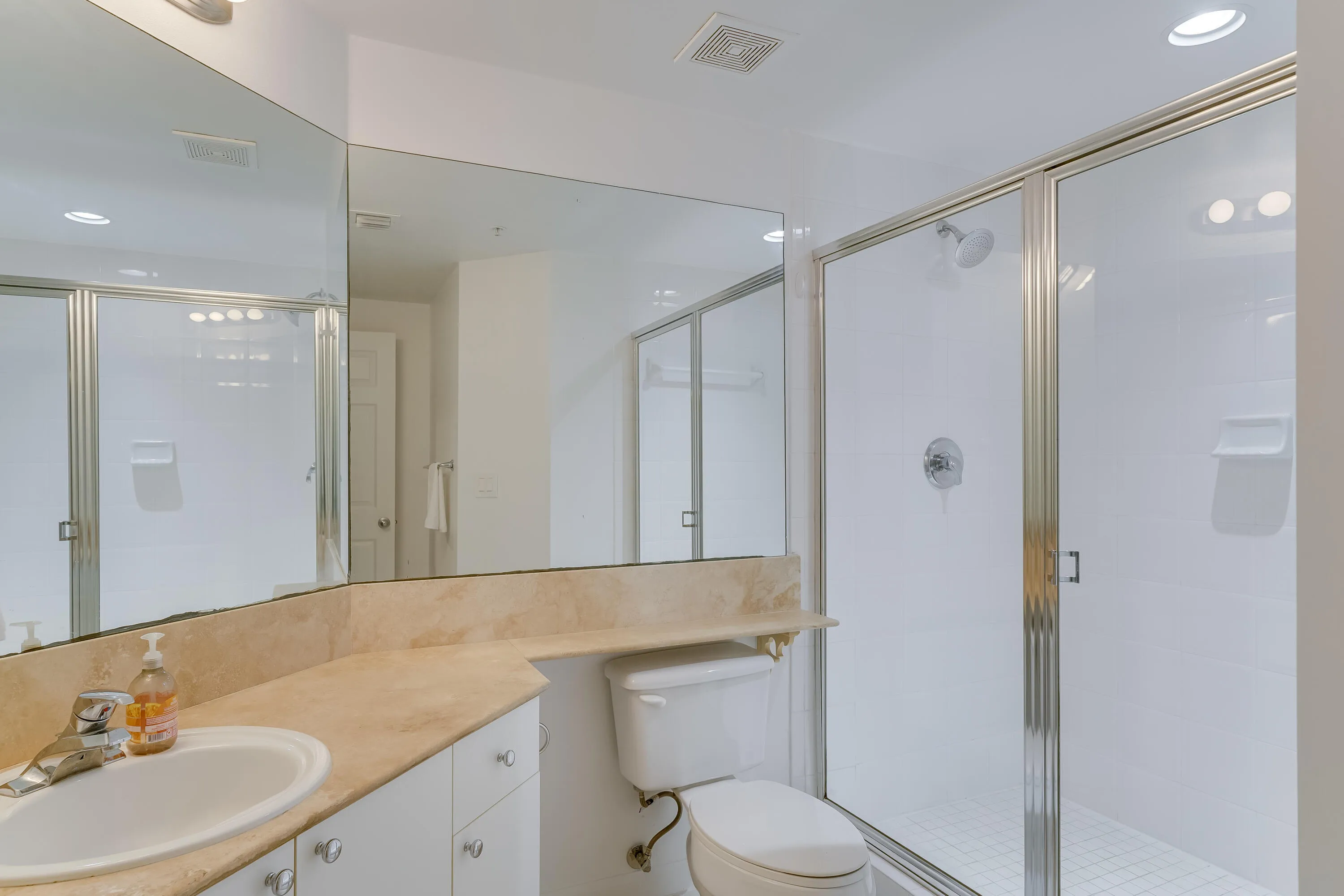 Bathroom featuring an integrated vanity with an undermount sink, a stone-finish countertop, a frameless mirror, a glass-enclosed shower with a tiled floor, and recessed lighting