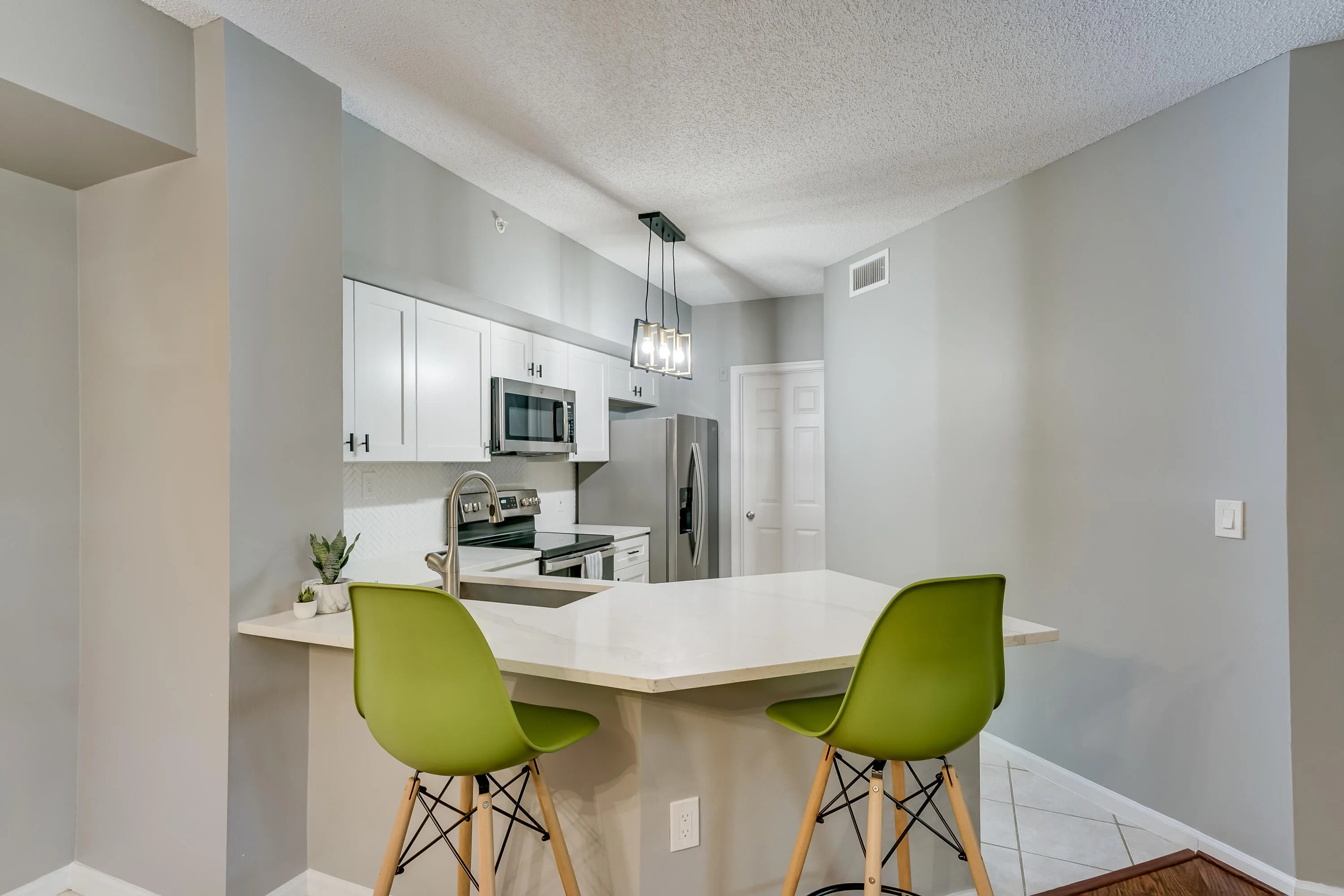 Kitchen featuring white shaker cabinetry, stainless steel appliances, and a peninsula with countertop seating