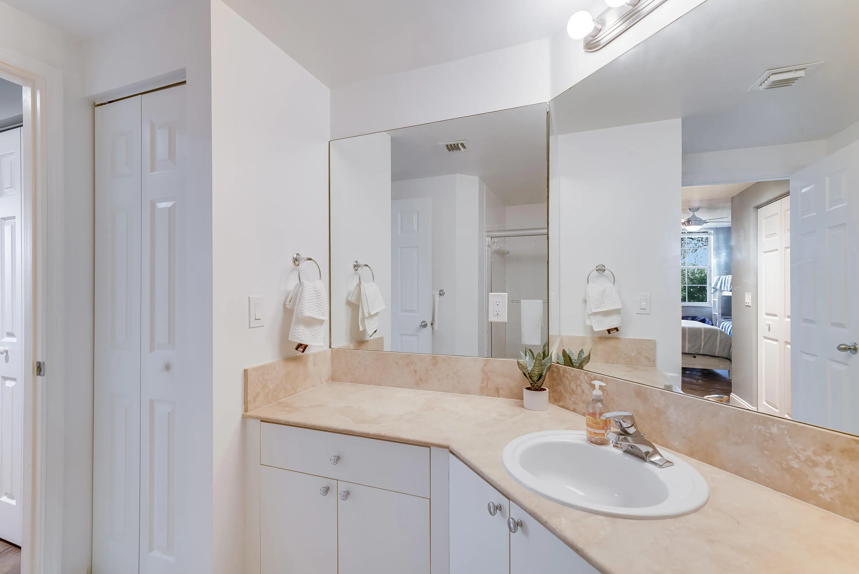 Bathroom vanity featuring an integrated sink, polished chrome faucet, and a large wall-mounted mirror