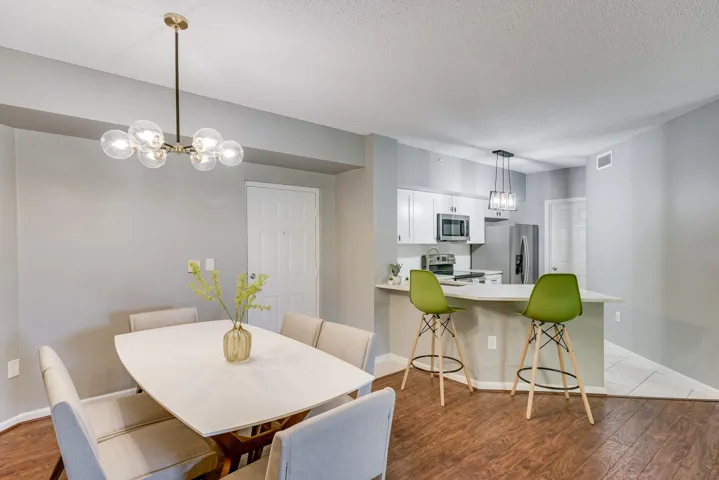 Open-concept living space featuring wood-finish flooring, a modern chandelier, and a breakfast bar with pendant lighting