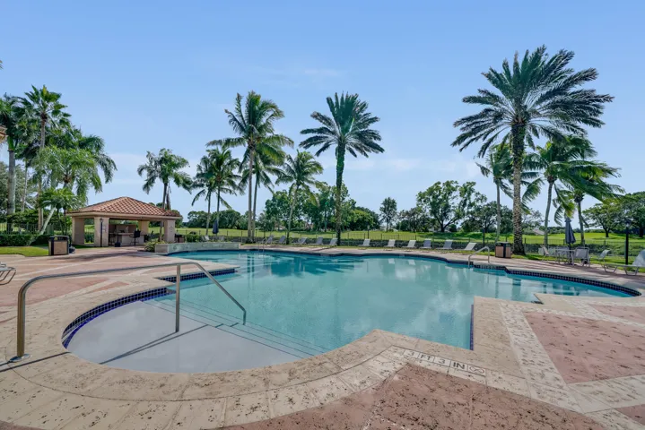 Expansive outdoor swimming pool with integrated spa, surrounded by a paver deck
