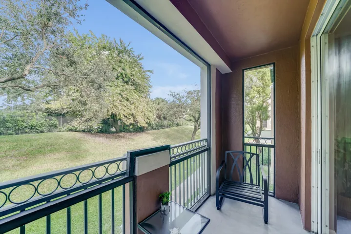 Balcony featuring a decorative black metal railing, concrete flooring, and an exterior wall with a textured finish