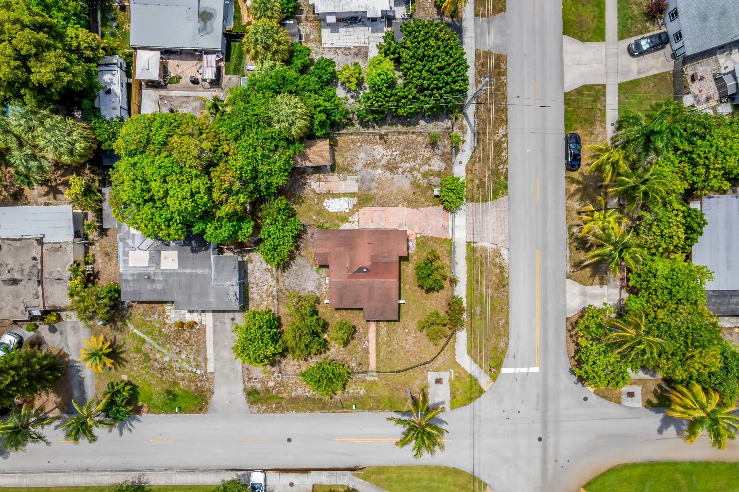 Aerial perspective showcasing a corner lot property with a single-story residence featuring a brown shingle roof