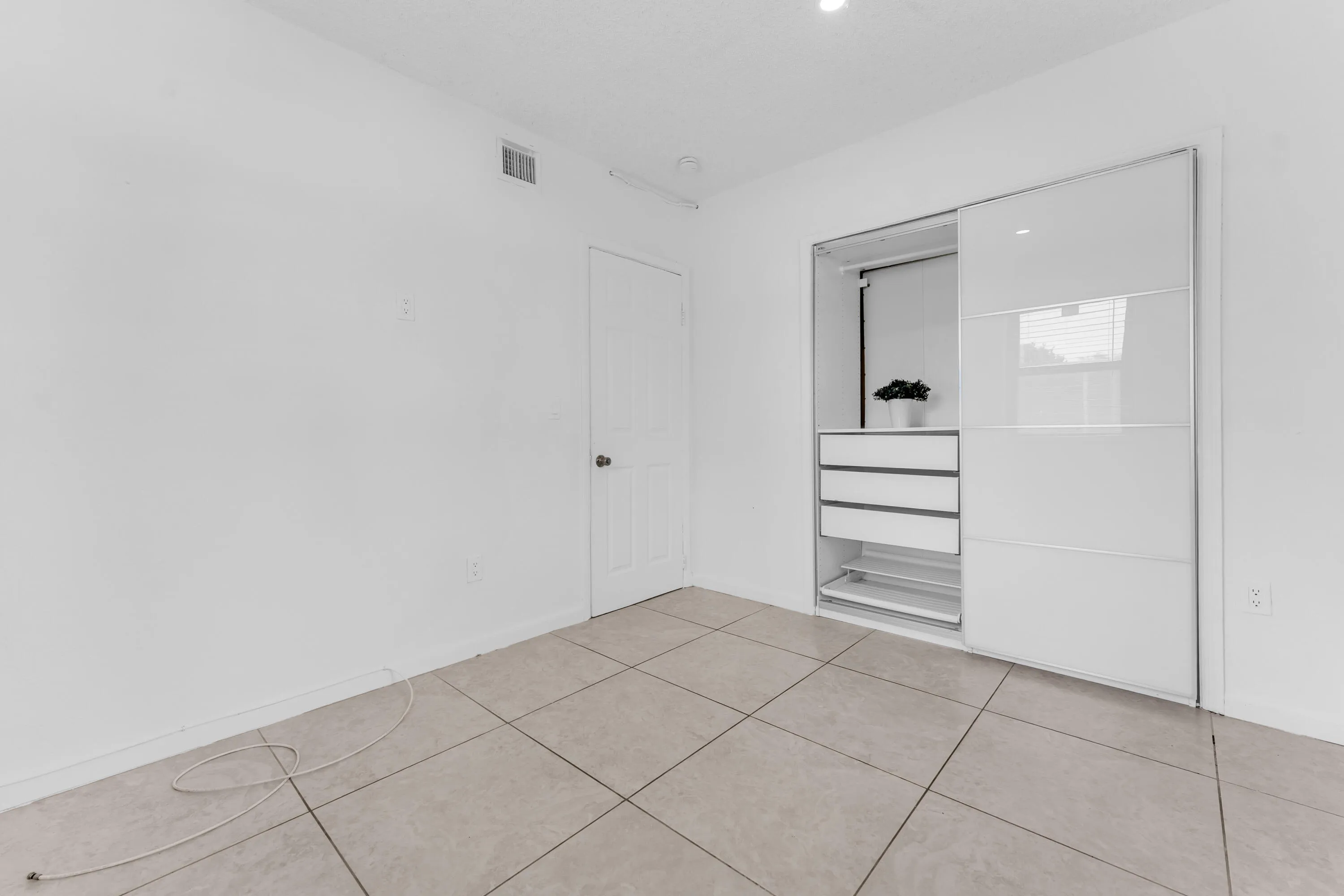 Recessed lighting illuminates a built-in closet with sliding doors, integrated drawers, and shelving