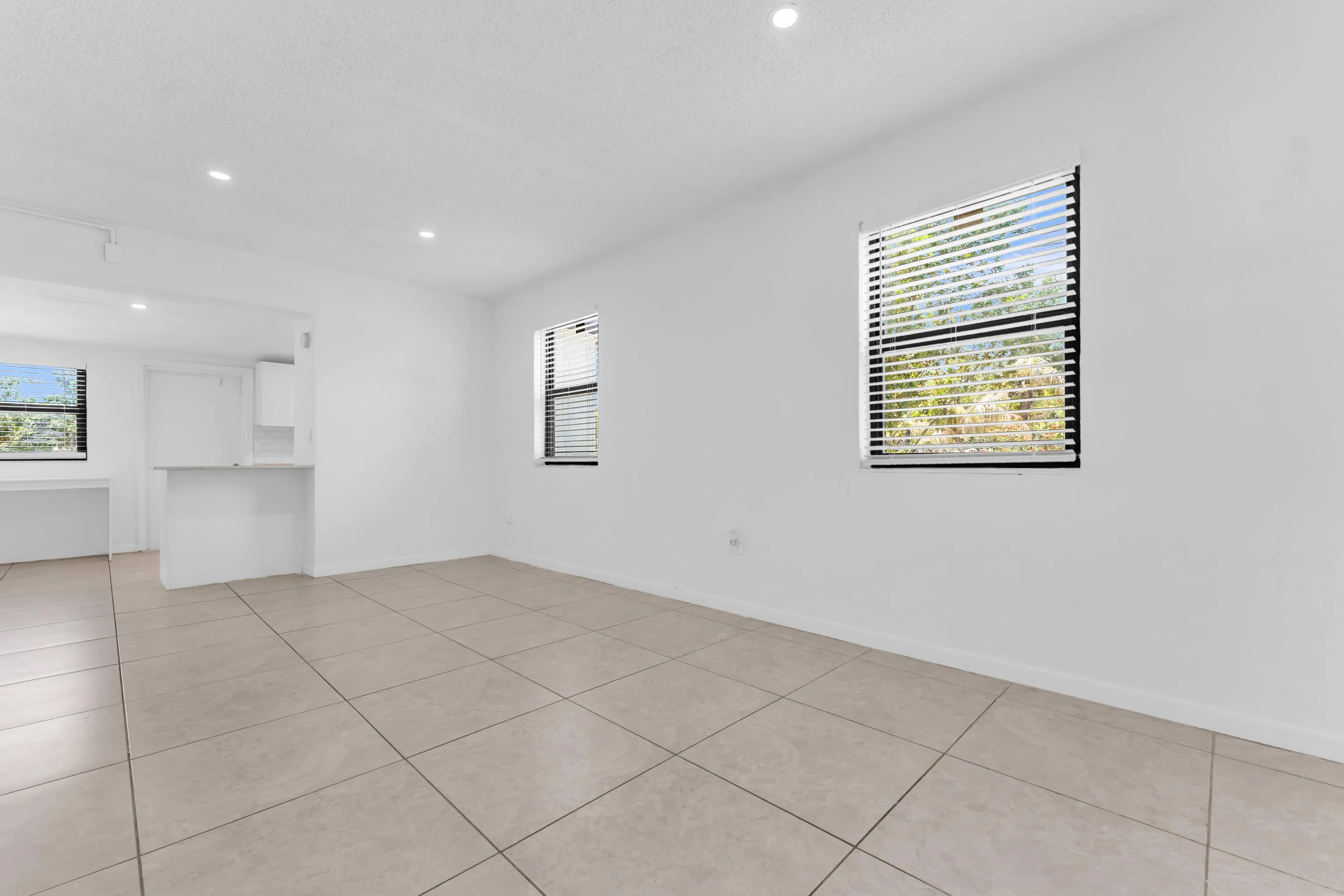 Spacious room featuring neutral-toned tile flooring, recessed lighting, and white walls
