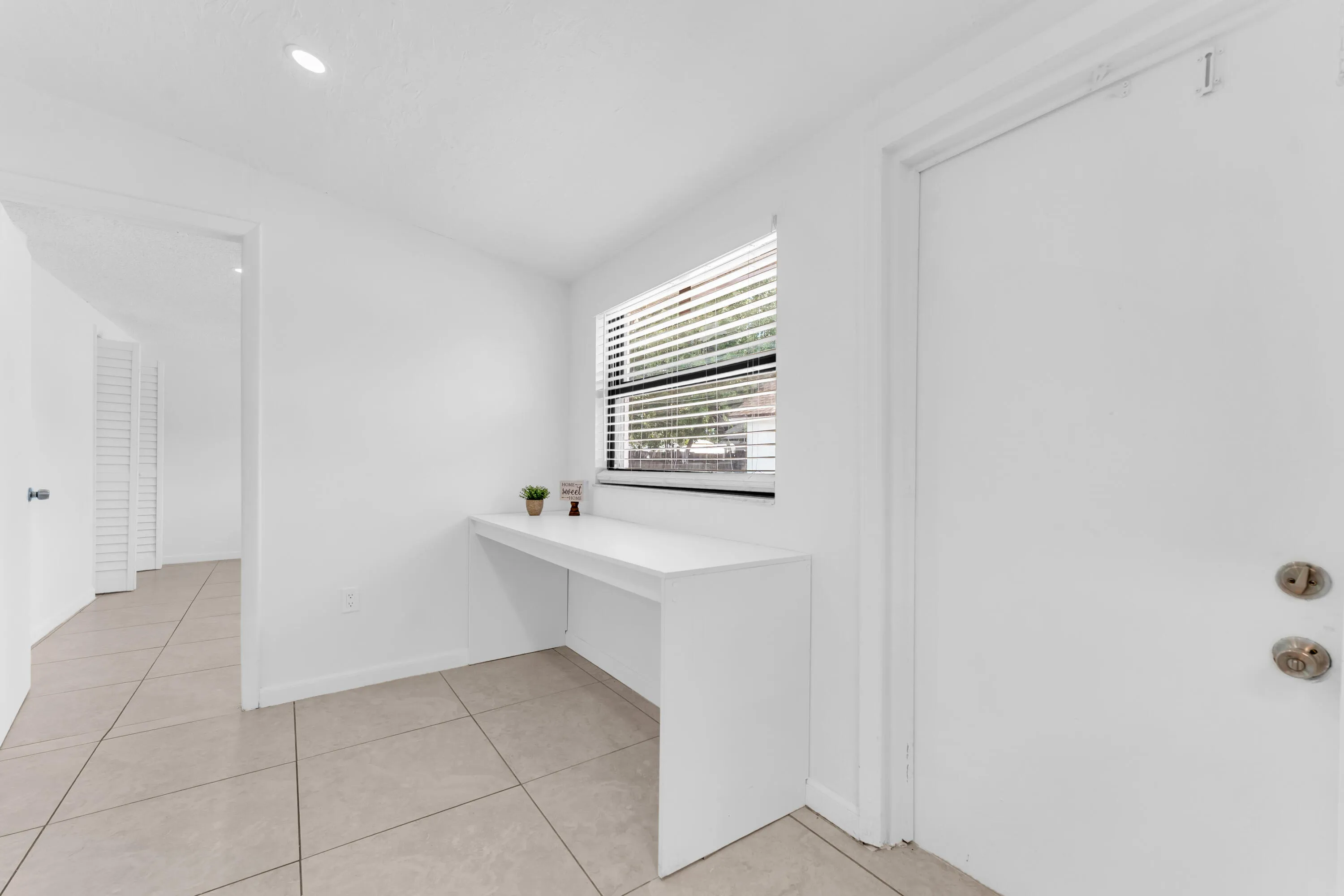 Integrated built-in desk with window, recessed lighting, and tile flooring