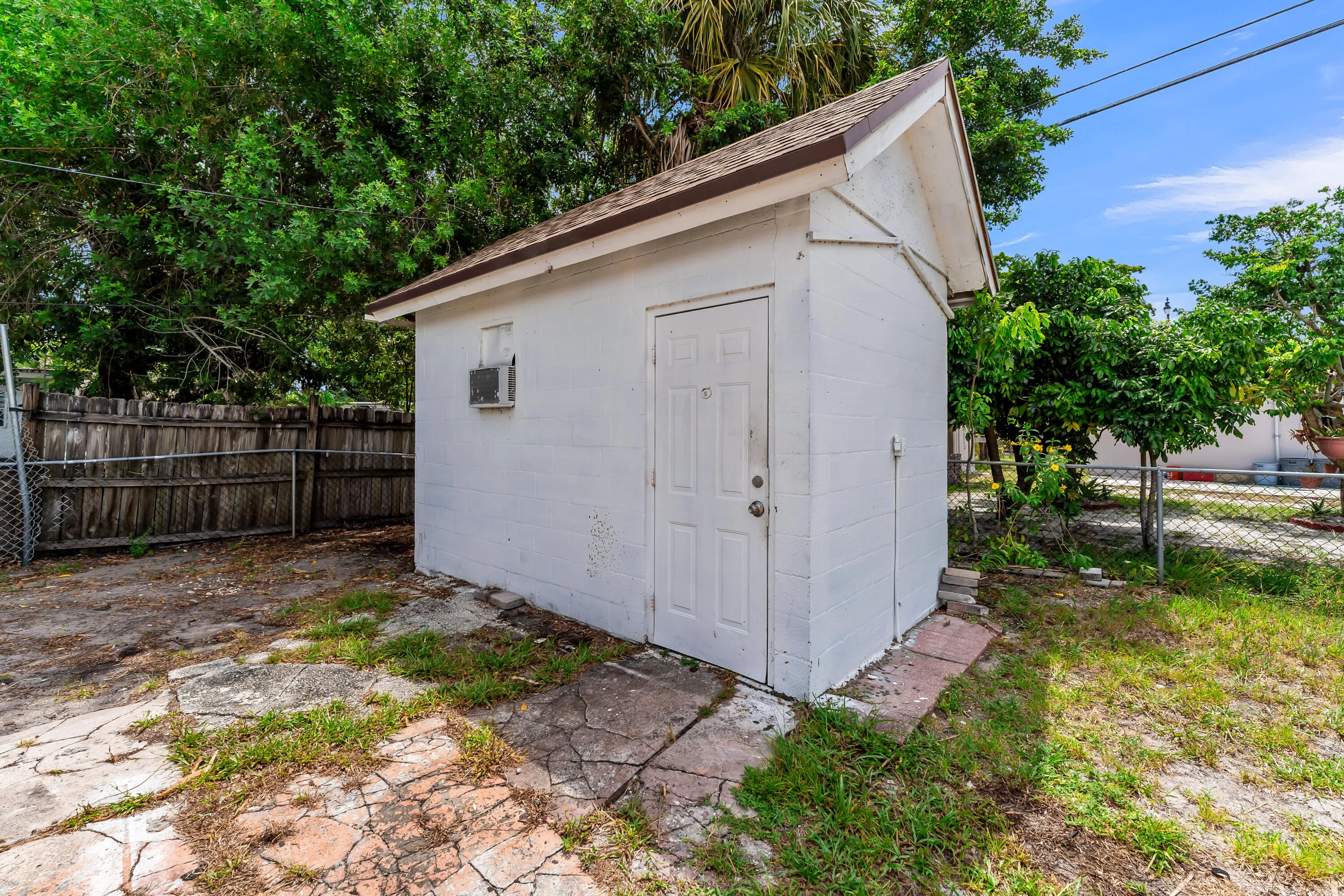 Detached storage building featuring a gable roof, white exterior, and a single entry door
