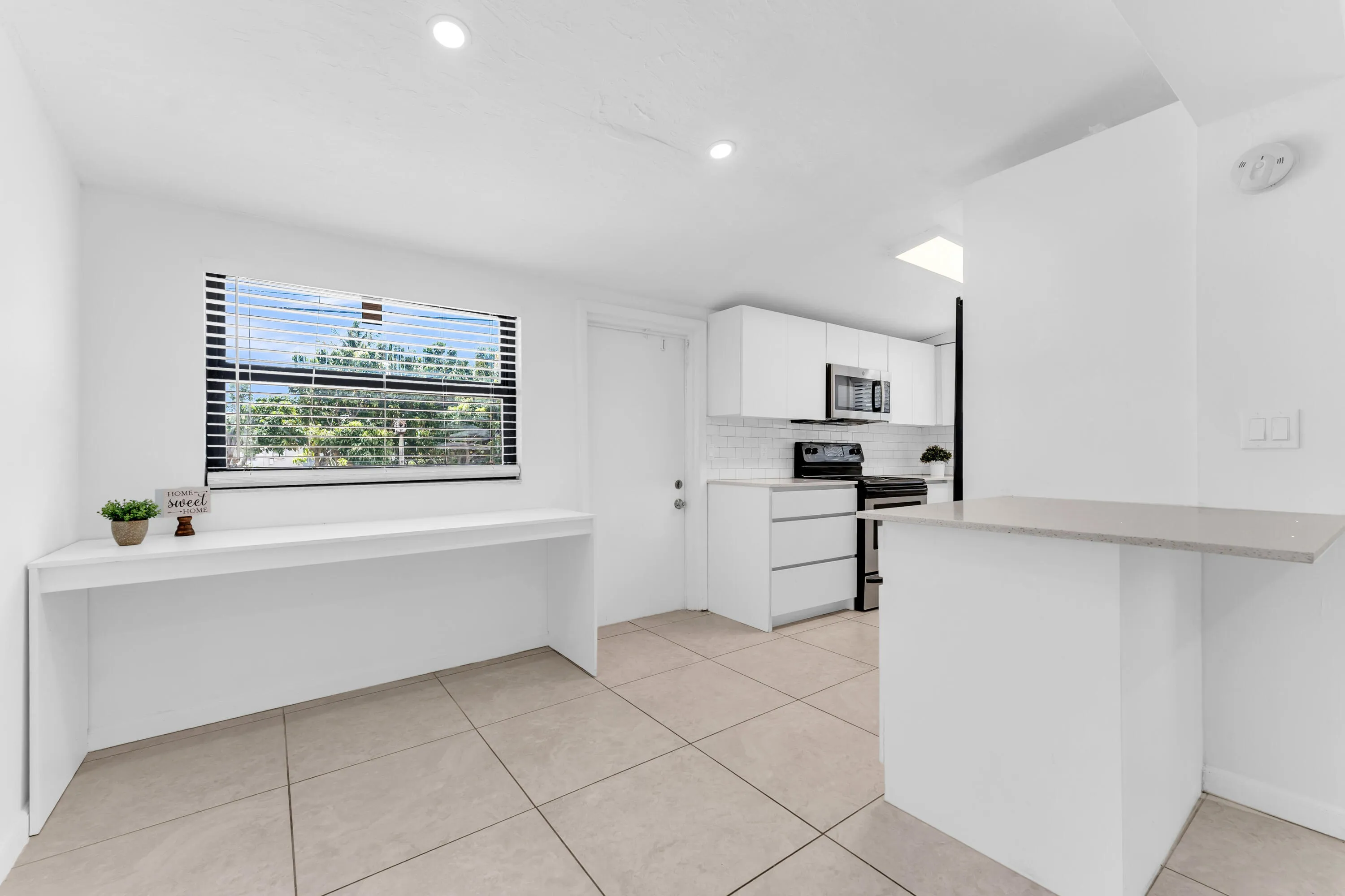 Kitchen area featuring a modern aesthetic with light-toned tiled flooring, white cabinetry, and stainless steel appliances