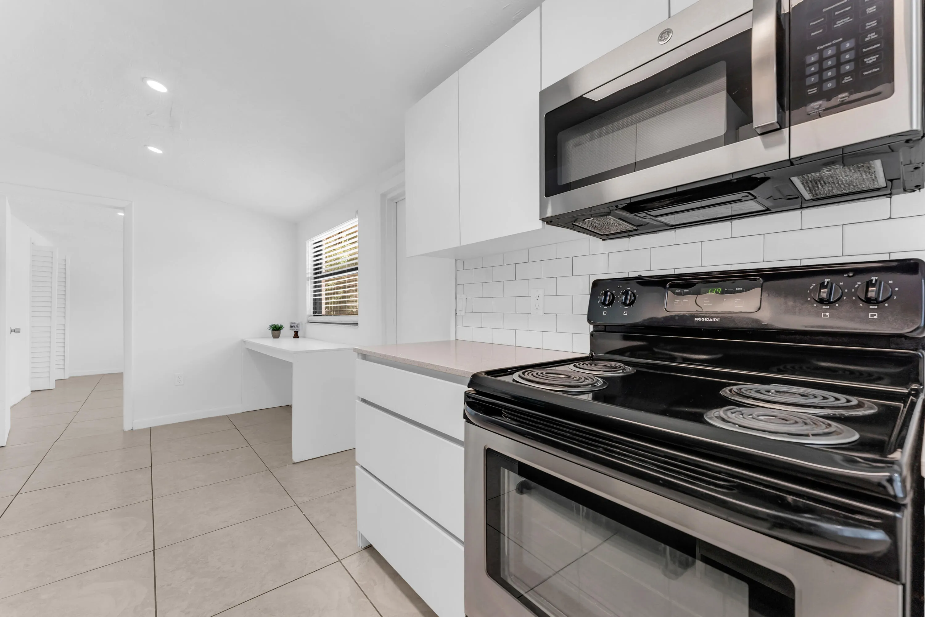Kitchen featuring white flat-panel cabinetry, light-toned countertops, and a white subway tile backsplash
