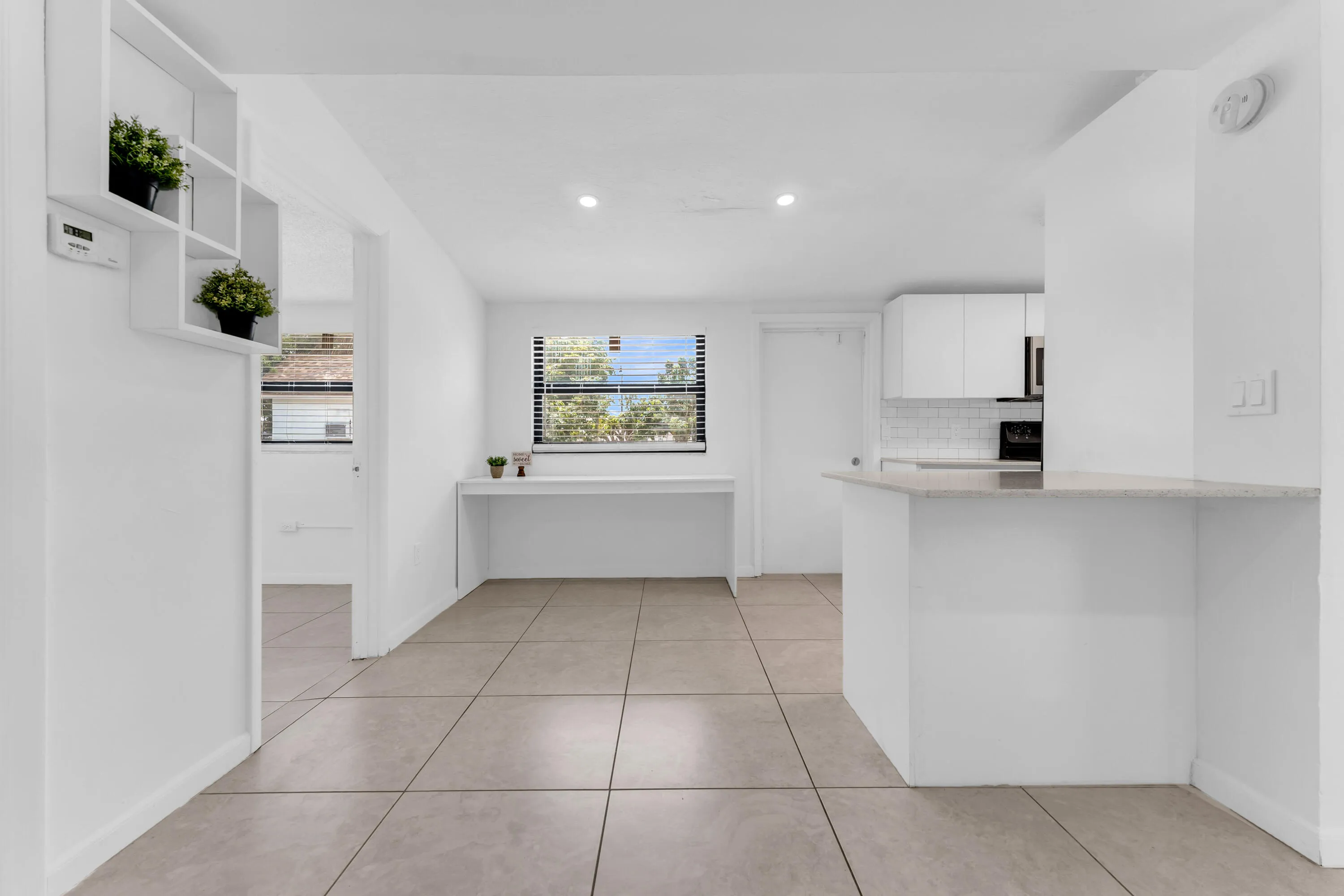 Open concept living area featuring large format tile flooring and a built-in desk space
