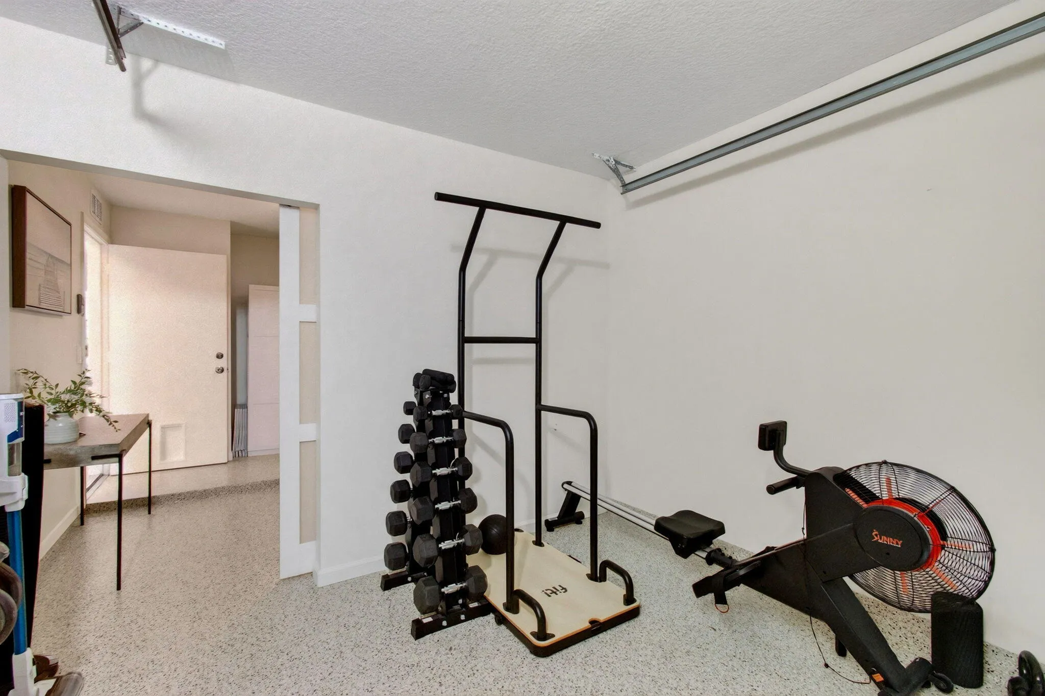 Garage space featuring a speckled epoxy floor, white painted walls, and an overhead garage door track system