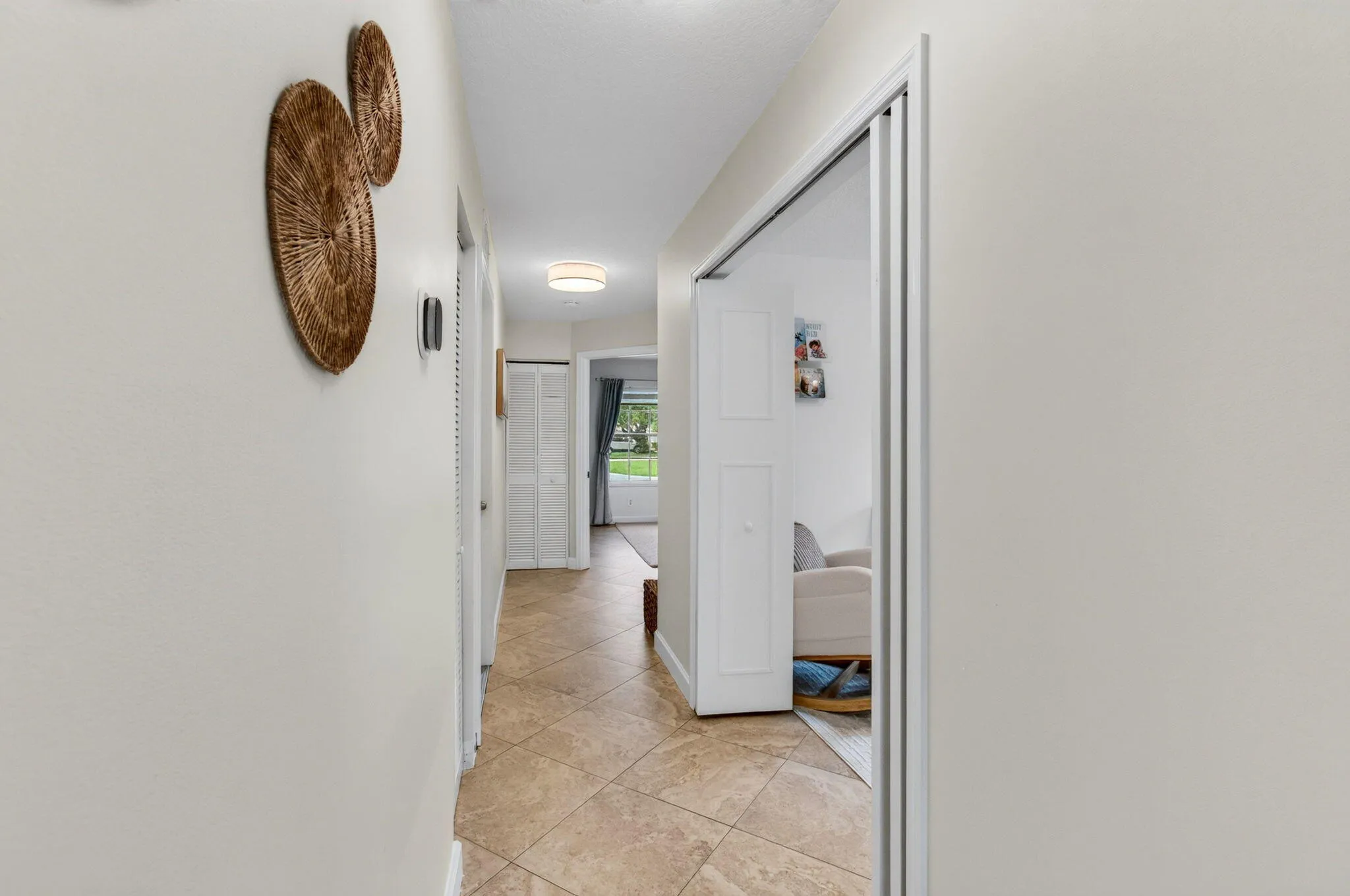 Hallway featuring tile flooring, neutral wall tones, white trim, and a flush-mount ceiling light