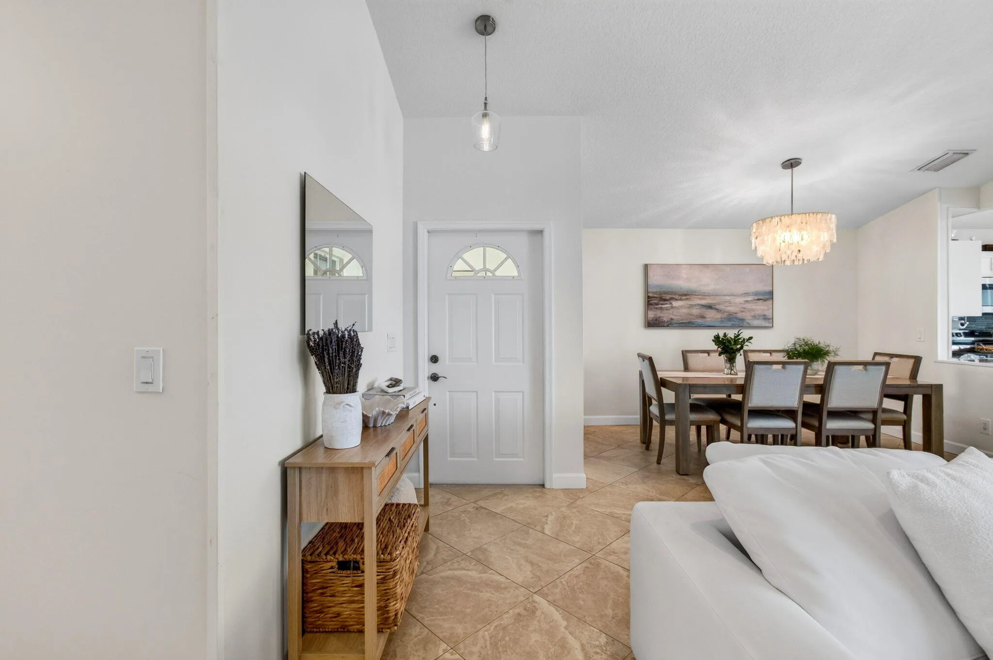 Entryway featuring a white paneled door with an arched glass insert, illuminated by an overhead pendant light