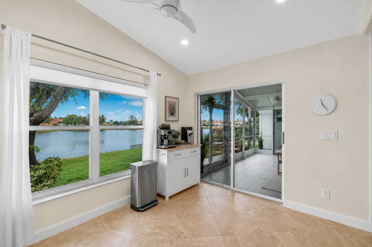 Interior space featuring tile flooring, a large window overlooking a large body of water, and sliding glass doors leading to a screened enclosure