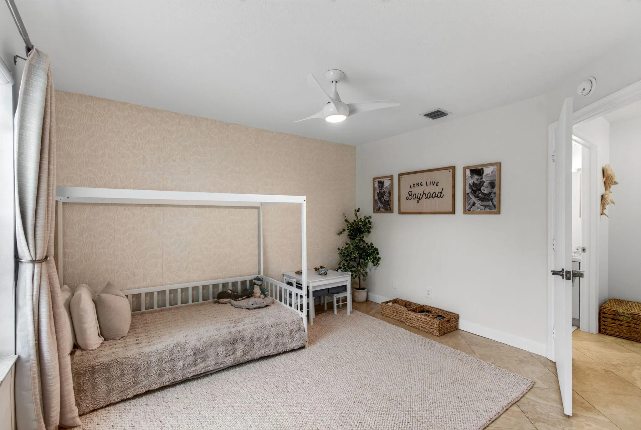 Bedroom featuring a patterned accent wall, white ceiling fan, and tile flooring