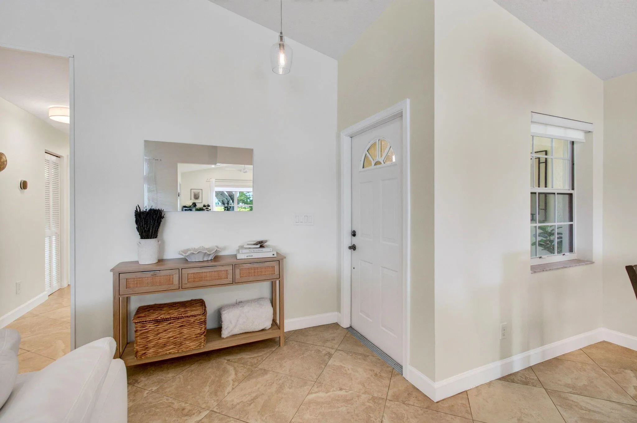 Entryway featuring a vaulted ceiling with a pendant light fixture, ceramic tile flooring, a white paneled door with an arched glass insert.