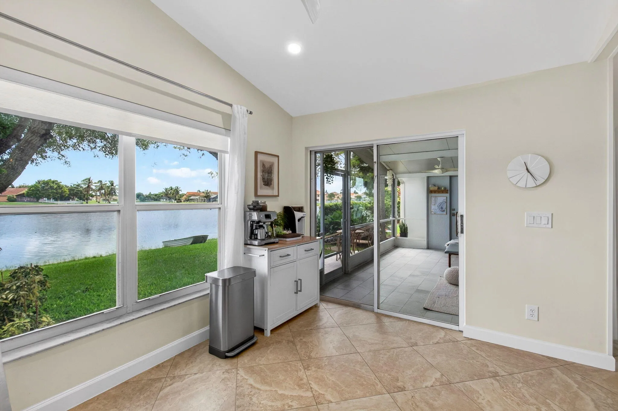 Interior space featuring tile flooring, a large window overlooking a large body of water, and sliding glass doors leading to a screened enclosure