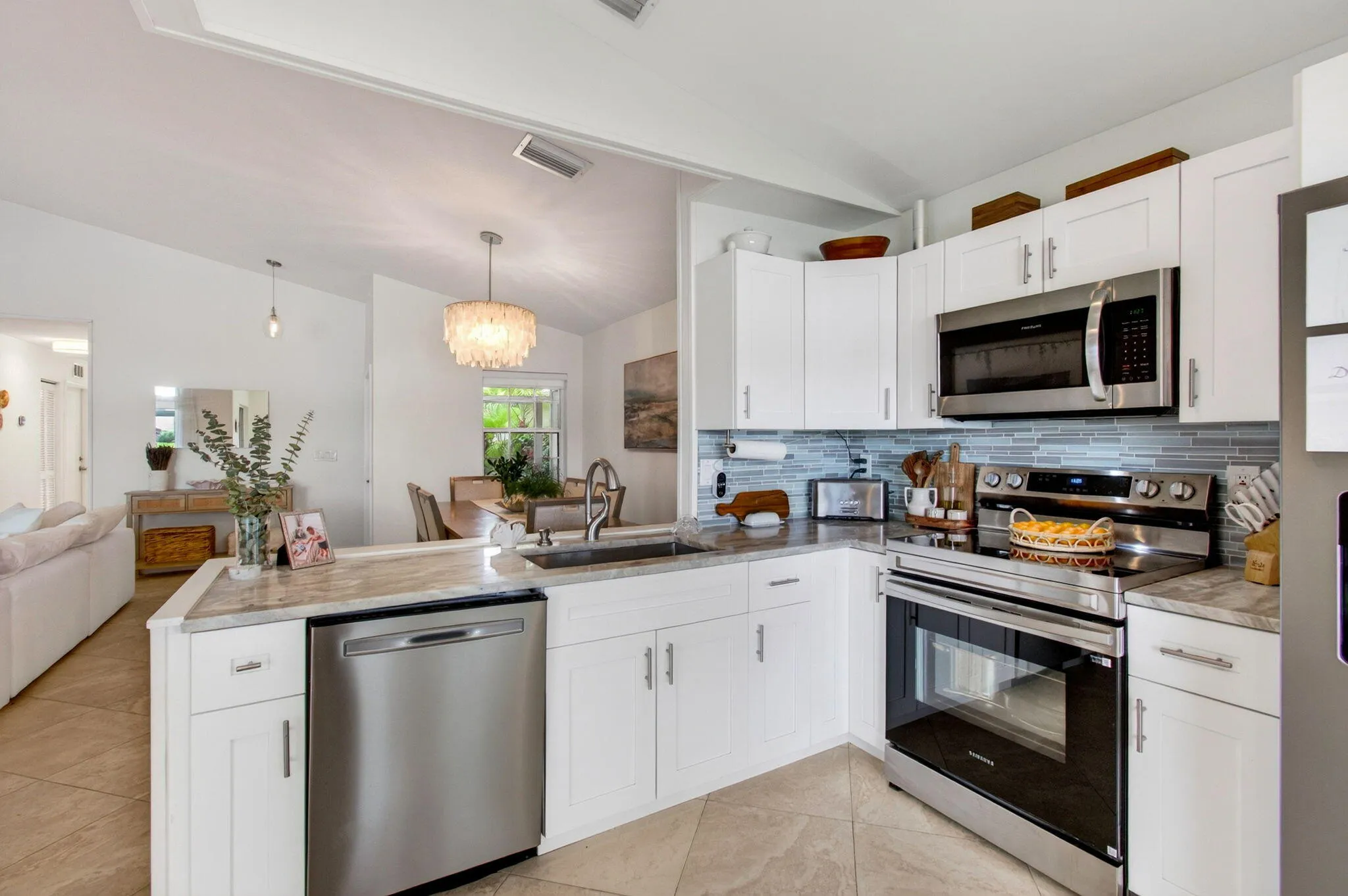 Modern kitchen featuring white cabinetry, stainless steel appliances, light-toned countertops, and a patterned tile backsplash