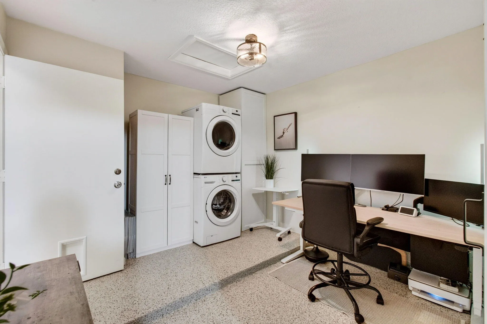 Integrated laundry area with stacked front-load washer and dryer, featuring white cabinetry for storage