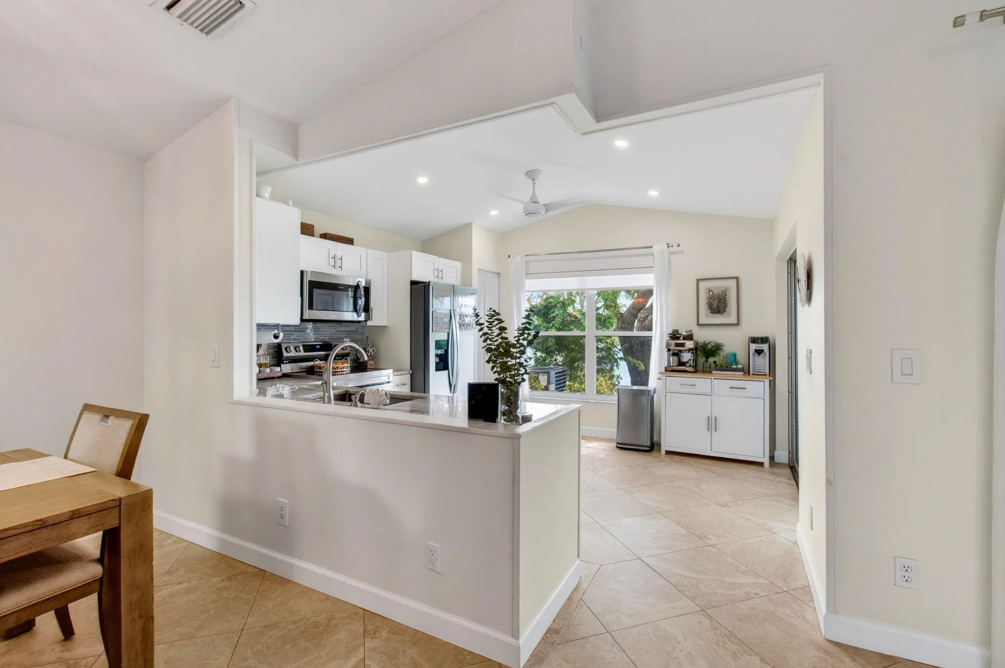 Open-concept kitchen featuring white cabinetry, stainless steel appliances, a tile backsplash, and a window overlooking exterior green space and lake