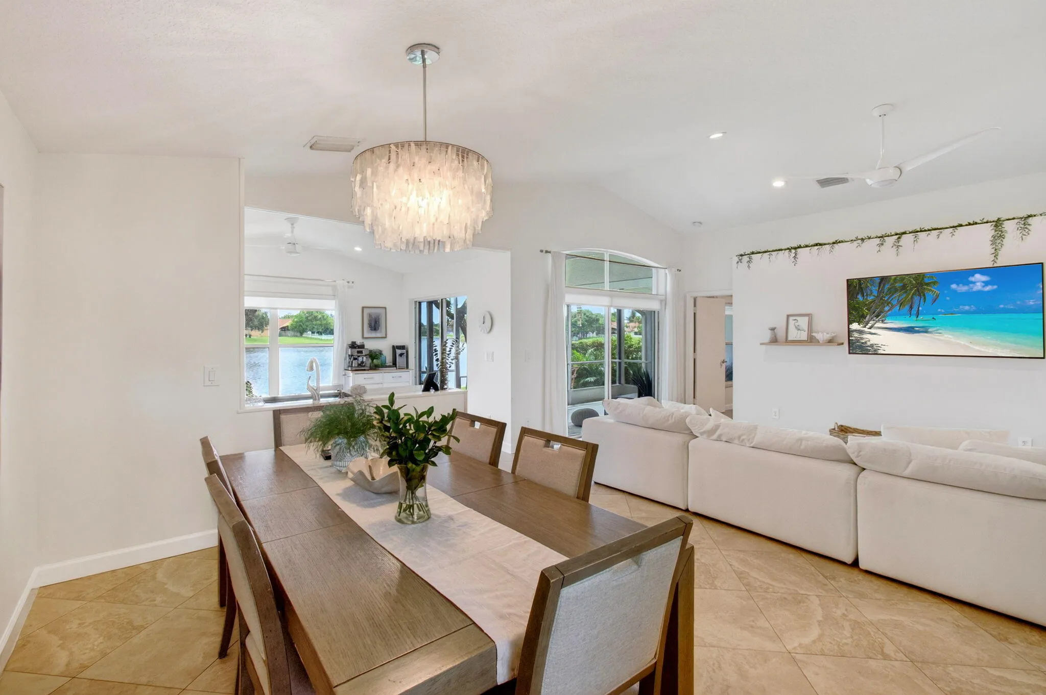 Open-concept living space featuring a contemporary chandelier, vaulted ceiling, and sliding glass doors