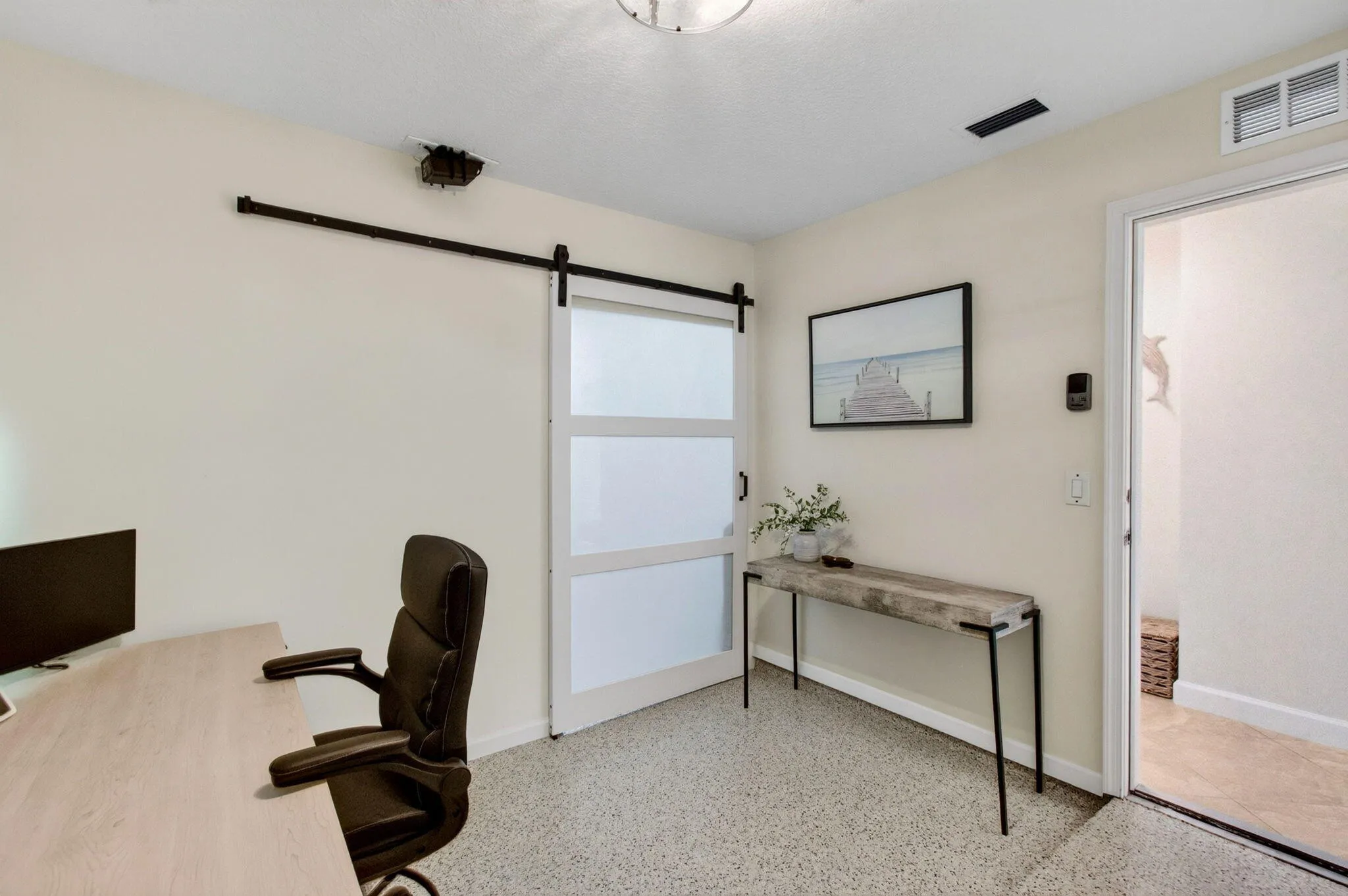 Room featuring a modern barn door with frosted glass panels, textured flooring, and light-toned walls
