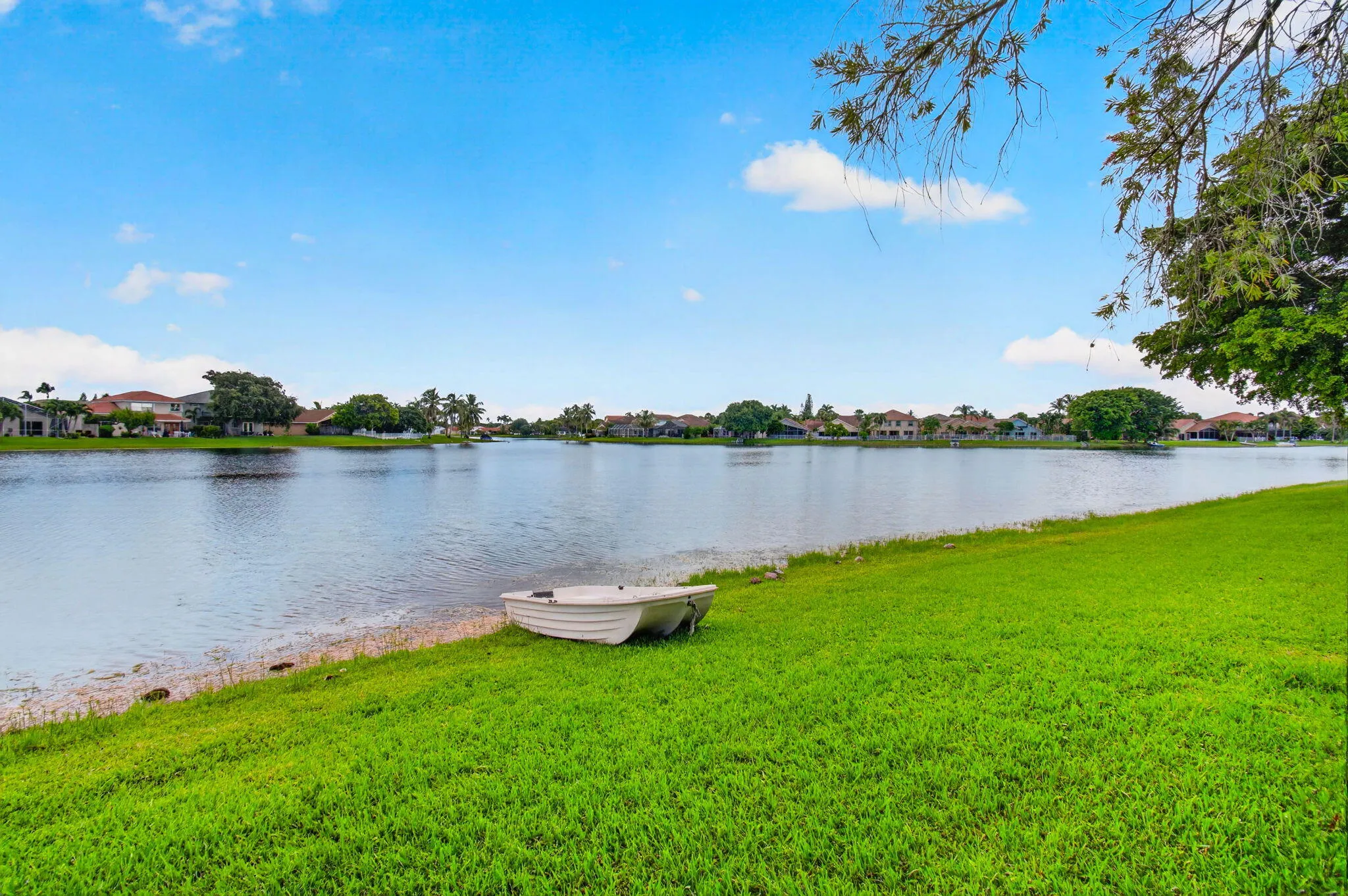 Waterfront property featuring a serene lake, lush green lawn, and mature trees