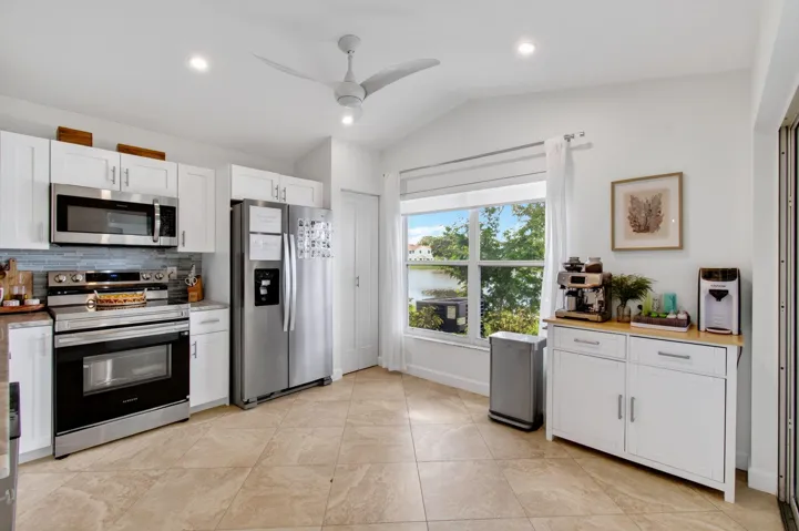Kitchen featuring white cabinetry, stainless steel appliances, tile flooring, recessed lighting, and a large window